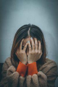 Young lady covering her face with her hands