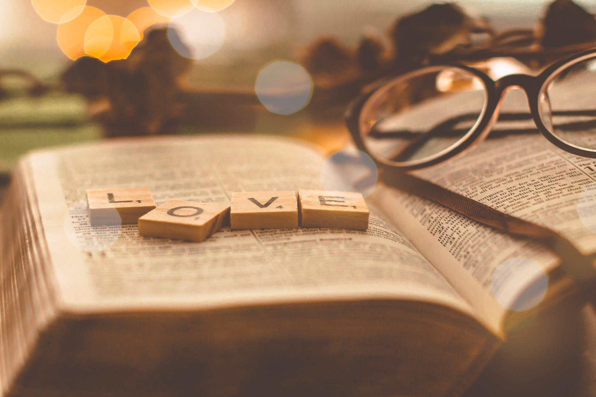An open bible with scrabble letters spelling out L O V E laying on the pages.