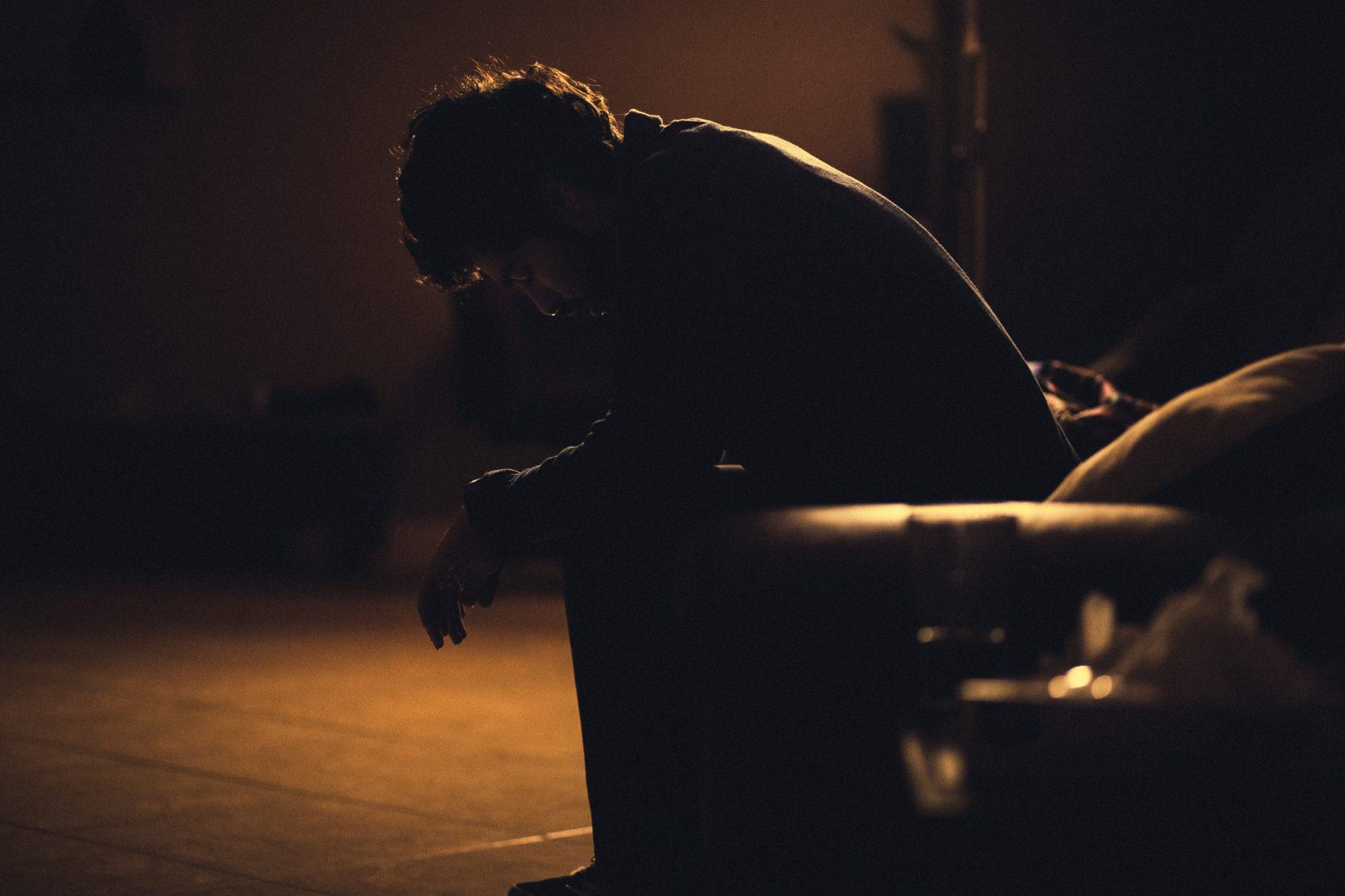 Man sitting in a dark room with his face in his hands.