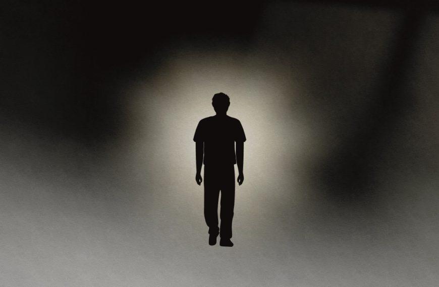 A shilouette of a man walking into a light.